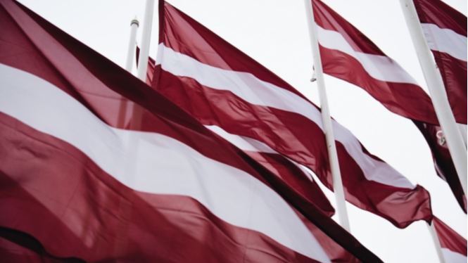 Vējā plīvo sarkanbalti sarkanie Latvijas valsts karogi